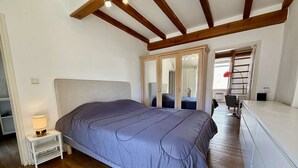 Un dormitorio con cama, mesita de noche y espejo.