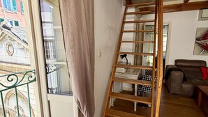 Una escalera de madera en una habitación con una ventana, un sofá y una mesita.