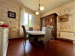 A dining area with a round table, four chairs, a wooden cabinet, and a radiator. - Spacious house in quiet area - 6 guests (Saint-Georges-d'Oléron)