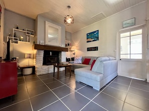 A living room with a fireplace, a sofa, a coffee table, and a television. - Spacious house in quiet area - 6 guests (Saint-Georges-d'Oléron)