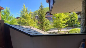 Een balkon met uitzicht op een woongebied, een stenen muur en een houten terras.