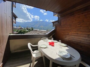 Un coin repas avec une table dressée pour quatre personnes, donnant sur un paysage montagneux.