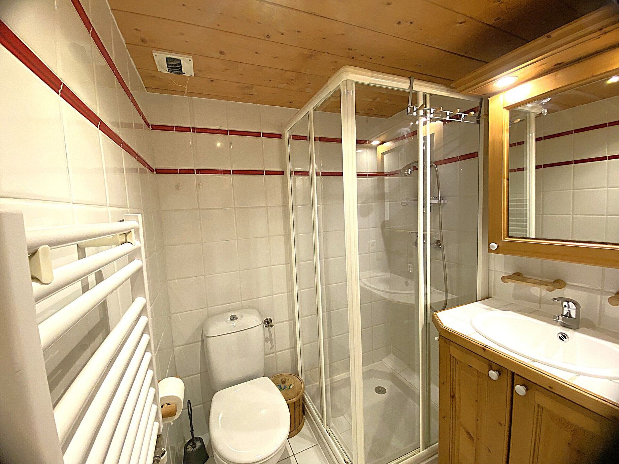 Un baño con inodoro, cabina de ducha, lavabo y espejo.