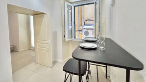 A small dining area with a table, chairs, and a window with an open door. - Apartment with air conditioning, central Ajaccio (Ajaccio)