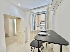 A small dining area with a table, chairs, and a window with an open door. - Apartment with air conditioning, central Ajaccio (Ajaccio)