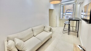 A modern living room with a sofa, a dining table with stools, a pendant light, and a view through a window. - Apartment with air conditioning, central Ajaccio (Ajaccio)