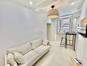 A modern living room with a sofa, a dining table with stools, a pendant light, and a view through a window. - Apartment with air conditioning, central Ajaccio (Ajaccio)