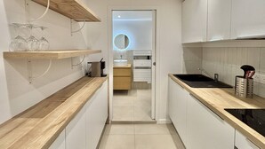 A modern kitchen with wooden countertops, a black sink, and a built-in oven. There are shelves with glassware and a coffee machine. - Apartment with air conditioning, central Ajaccio (Ajaccio)