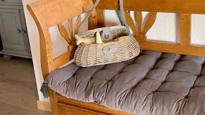 Een houten bank met een bekleed zitvlak en een geweven mand erop.