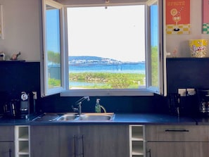 A kitchen with a large window, a sink, and a coffee machine. - Unique house, pond view - 4 guests (Mèze)