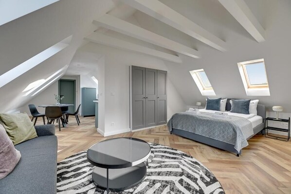 Une chambre de style loft moderne, dotée d’une lucarne, d’un lit, d’un canapé et d’un coin repas.