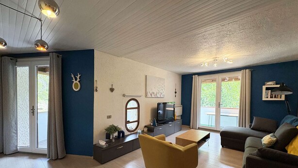En stue med sofa, lænestol, fjernsyn og spisebord.