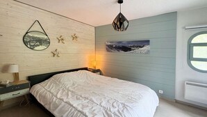 Et soveværelse med seng, natbord, lampe, et billede på væggen og et vindue.