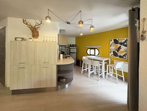 Eine moderne Küche mit einem Holzkorpus, einer Dekoration mit Hirschgeweih und einem Essbereich mit weißen Stühlen und einem Tisch.