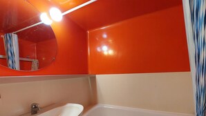 Une salle de bain avec un lavabo blanc, un miroir et une baignoire.