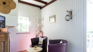 Ein Zimmer mit Holzboden, weißen Wänden, einem Fenster, einer Bücherwand und zwei Stühlen.