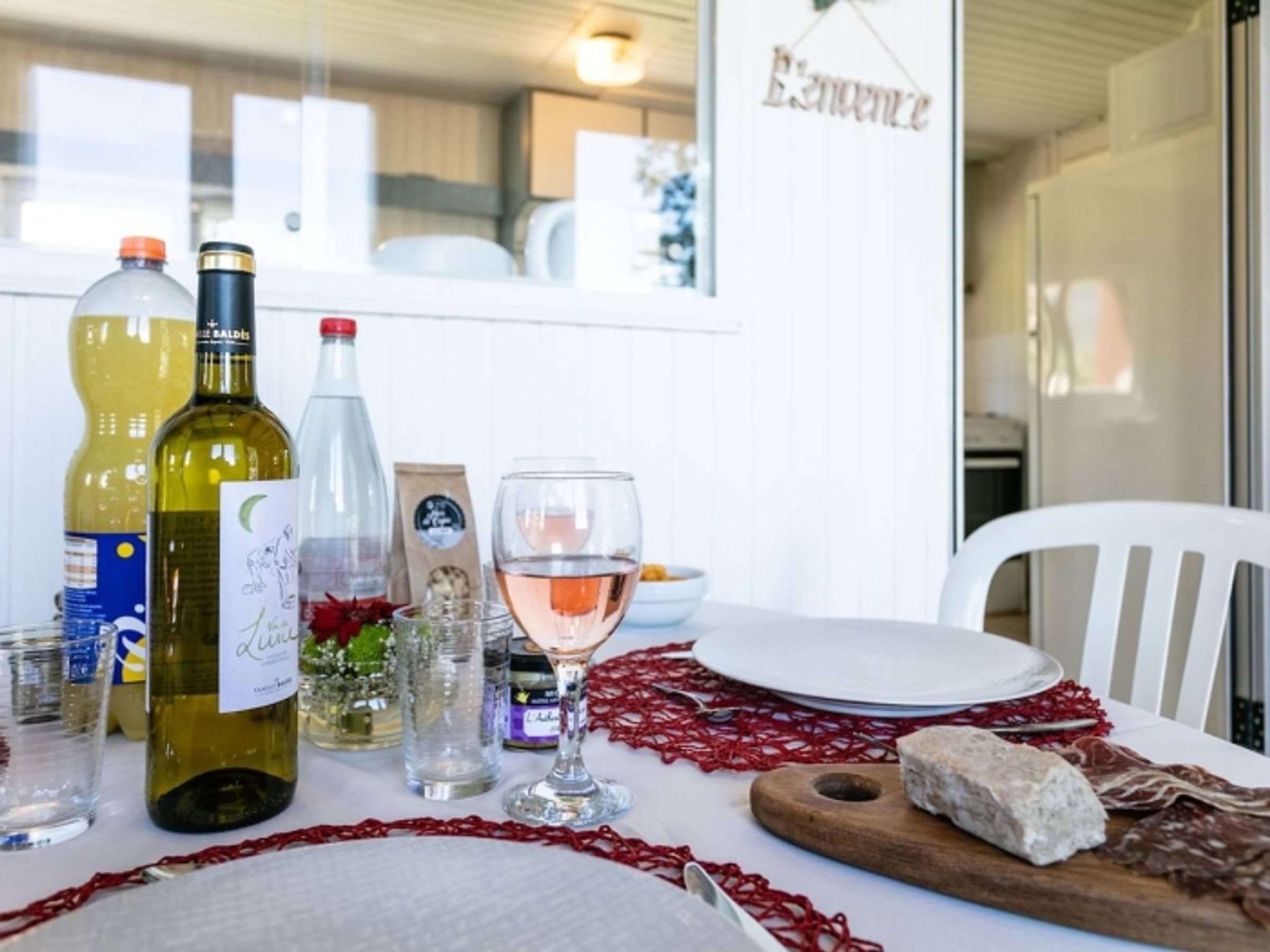 Une table à manger dressée avec des bouteilles de vin, des verres et une assiette remplie de nourriture.