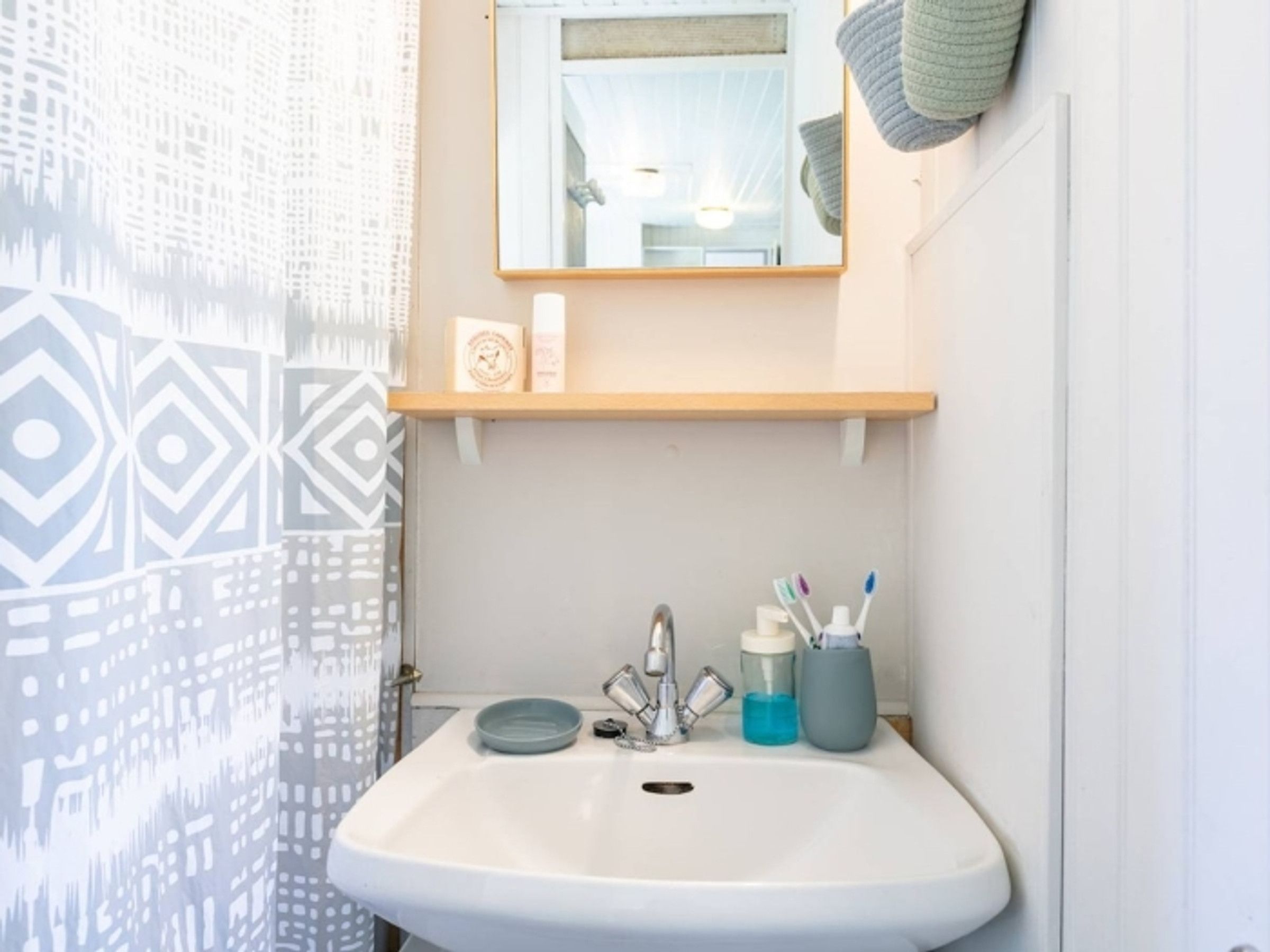 A bathroom with a white sink, a mirror above it, and a towel hanging on the wall.