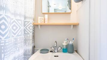 A bathroom with a white sink, a mirror above it, and a towel hanging on the wall.