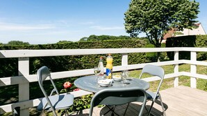 Ein runder Tisch mit Stühlen auf einer Terrasses, eine Wasserflasche und ein Glas Weißwein.
