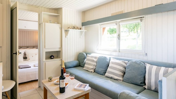 Ein gemütliches Zimmer mit einem Bett, einem Sofa, einem Tisch mit einer Flasche und Gläsern sowie einem Fenster mit Blick.