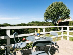 An outdoor dining area with a round table and two chairs, a bottle of water, a glass of white wine, and a bottle of beer. - Cozy chalet, parking, pets welcome - 3 guests (Le Vigan)