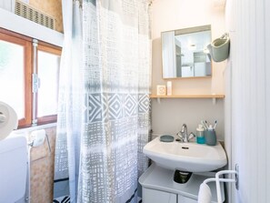 A bathroom with a shower curtain, a sink, a mirror, and a towel rack. - Cozy chalet, parking, pets welcome - 3 guests (Le Vigan)