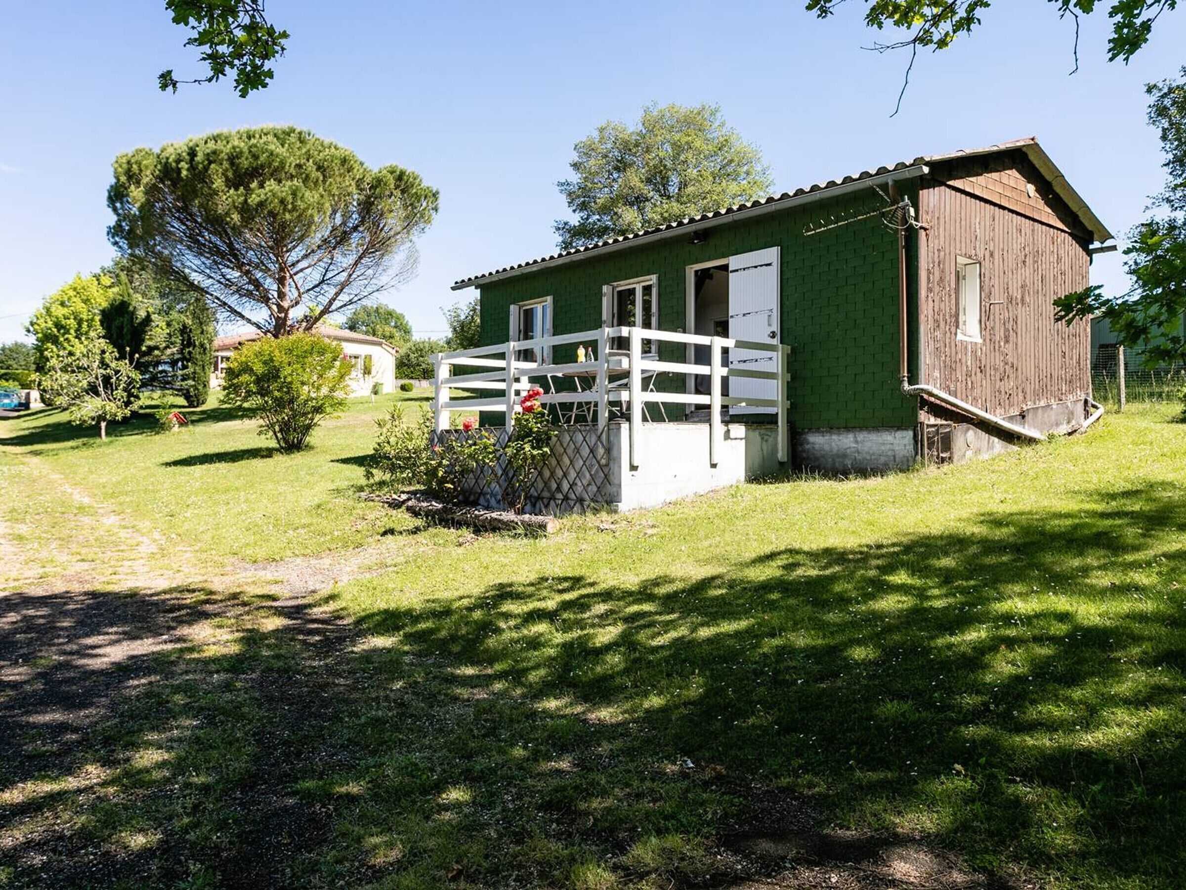 A single-story building with a fenced porch, a small garden, and a clear sky.. Cozy chalet, parking, pets welcome - 3 guests