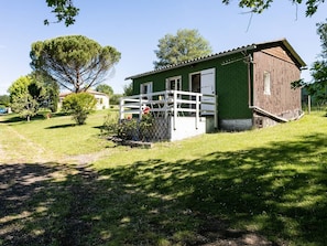 A single-story building with a fenced porch, a small garden, and a clear sky.