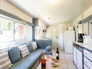 A compact RV kitchen with a dining area, a sofa, and a refrigerator.