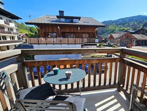 Ein Balkon mit Tisch und Stühlen mit Blick auf eine Berglandschaft und ein Dorf.