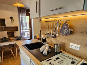 Eine moderne Küche mit Holzschnitzereien, einer schwarzen Arbeitsplatte und einer hängenden Küchenutensilienstange.