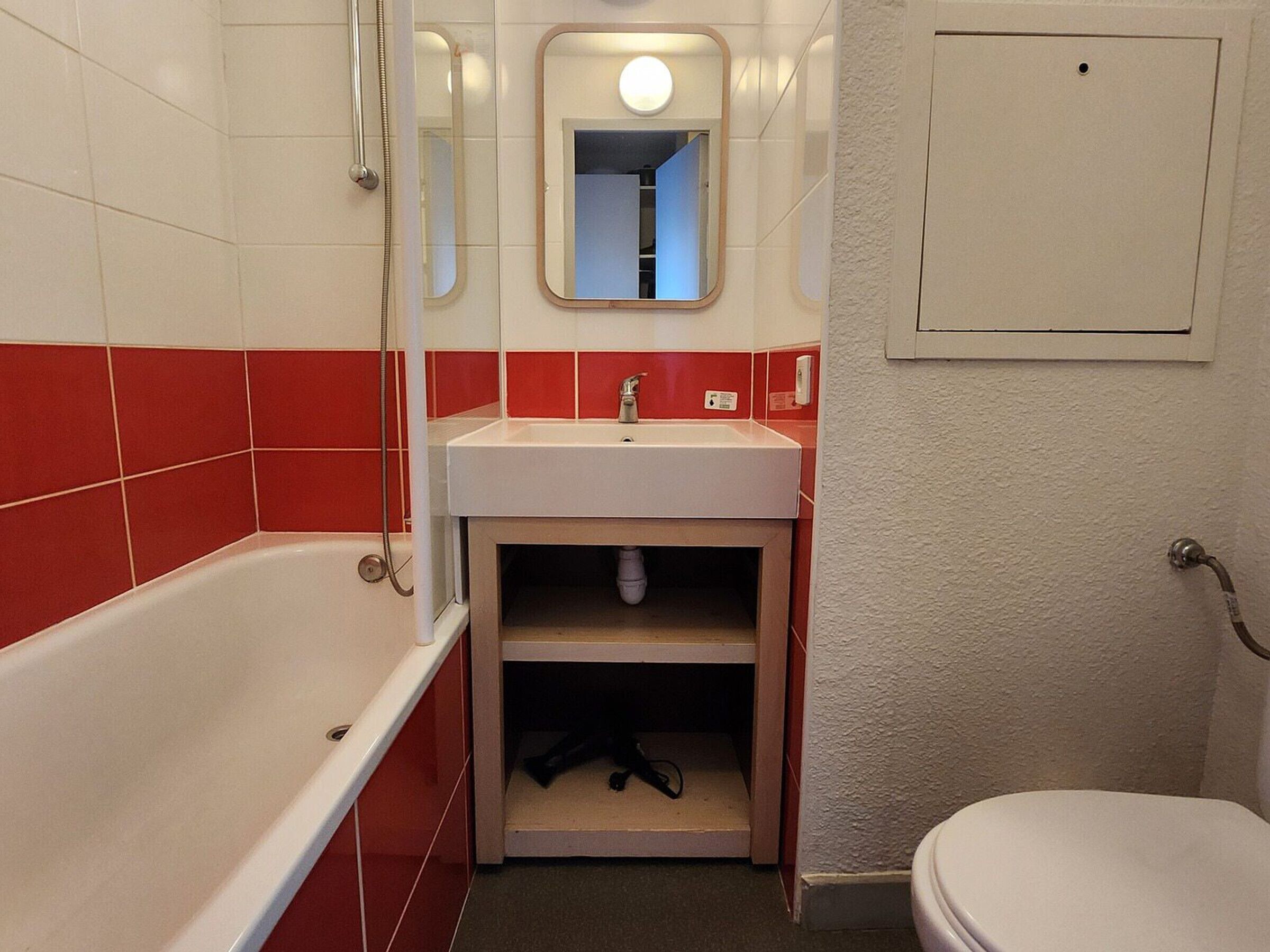 A bathroom with a bathtub, sink, mirror, and toilet.