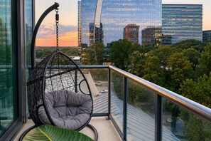 A balcony with a hanging chair, a view of a cityscape with modern buildings, and a clear sky. - Luxury Buckhead Stay with Skyline Views (Atlanta)