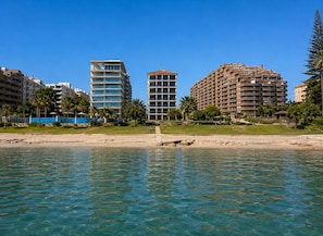 Ein Strandhotel mit mehreren Hochhäusern, klarem, blauem Wasser und Palmen.