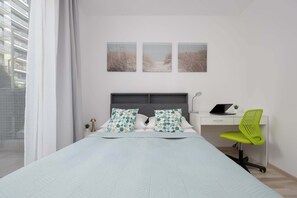 A bedroom with a bed, a desk, a chair, and three wall-mounted pictures. - Modern Apartment with a Garden | A Place to Work (Warszawa)