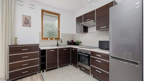 Una cocina moderna con alacenas de madera oscura, un refrigerador de acero inoxidable y un horno empotrado.