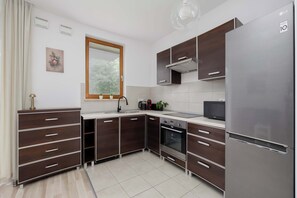 Una cocina moderna con alacenas de madera oscura, un refrigerador de acero inoxidable y un horno empotrado.