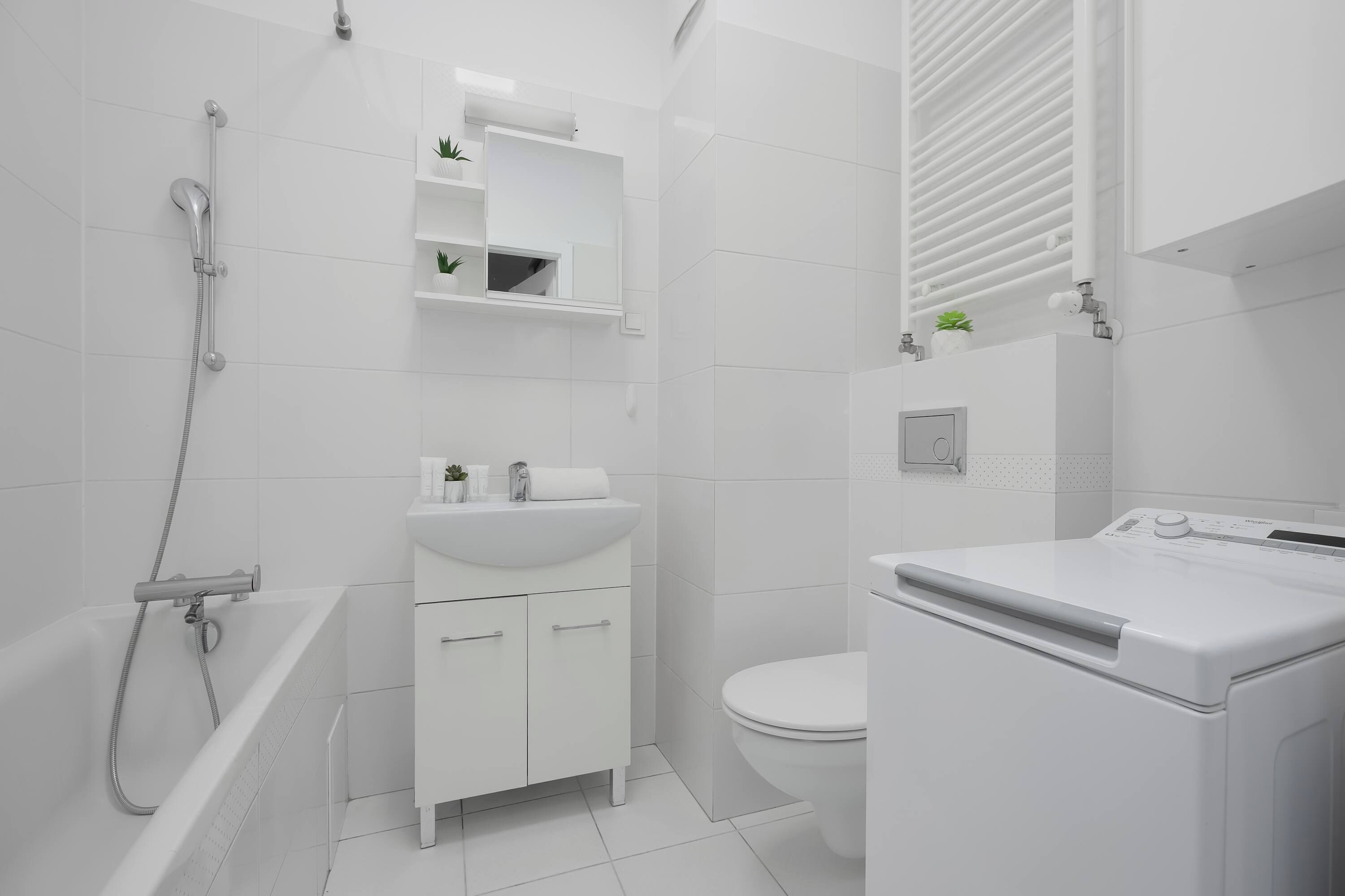 A modern bathroom with a bathtub, toilet, and washing machine.