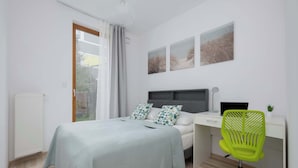 Un dormitorio con una cama, un escritorio, una silla y obras de arte en la pared.
