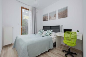 Un dormitorio con una cama, un escritorio, una silla y obras de arte en la pared.