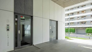 Entrada moderna de un edificio con puerta de cristal identificada con 'KASPRZKA 295 KL.B' y una secuencia numérica '083145' en la pared.