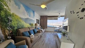 Una sala moderna con un conjunto de sofás, un televisor y un ventilador de techo.