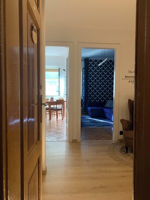 A hallway leading to a dining area with a table and chairs, a patterned wall, and a blue sofa. - Stock 22:modern, central and close to the sea! Experience the city and the beach on foot (Trieste)