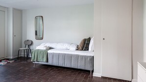 A bedroom with a bed, a chair, a mirror, and a door.