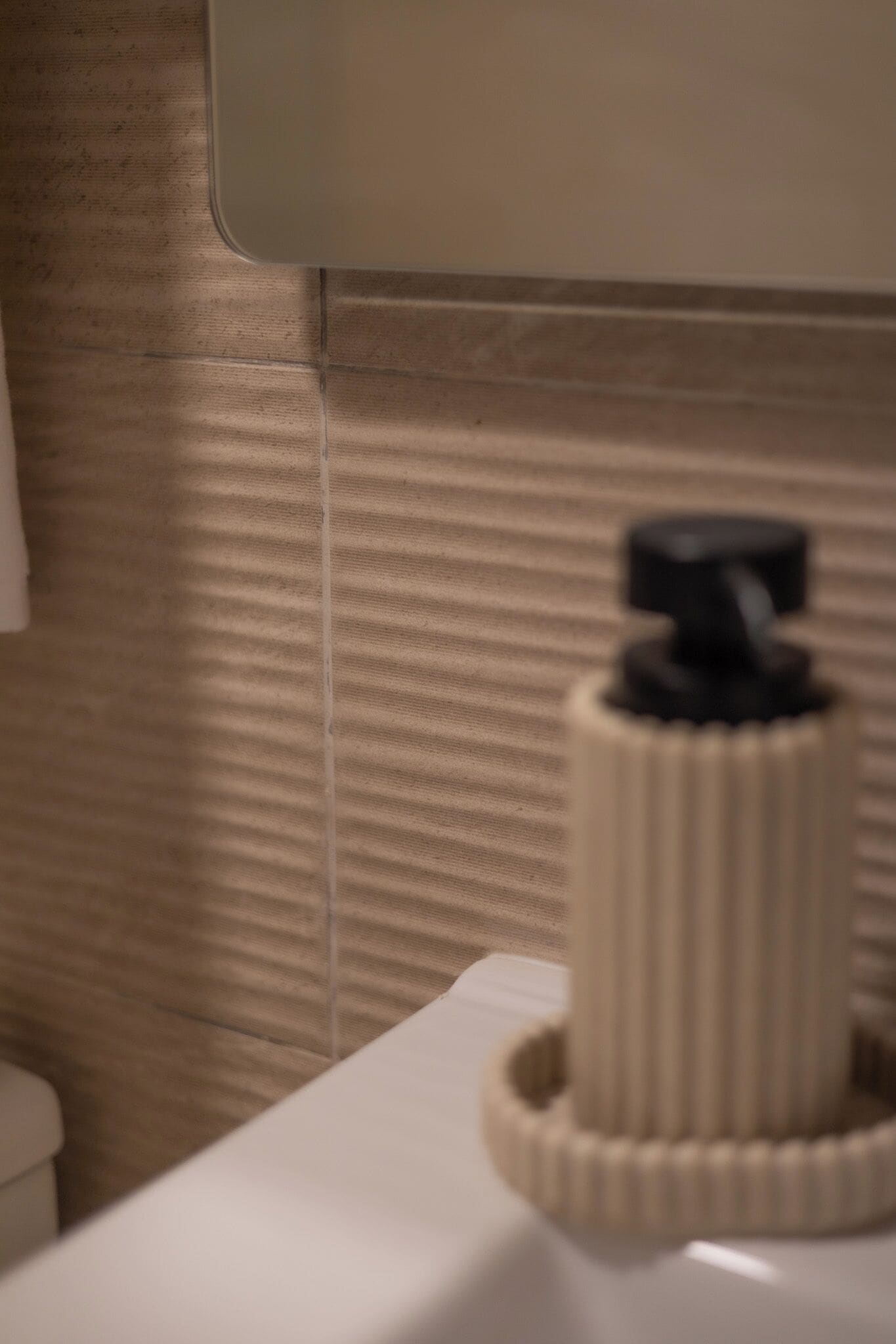 Ein Badezimmer mit strukturierter Wand, einem weißen Waschbecken und einem Handtuchhalter.