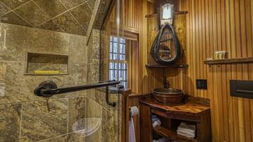 Une salle de bain avec un mur en pierre, un lambris en bois, un lavabo en bois et un porte-serviettes.