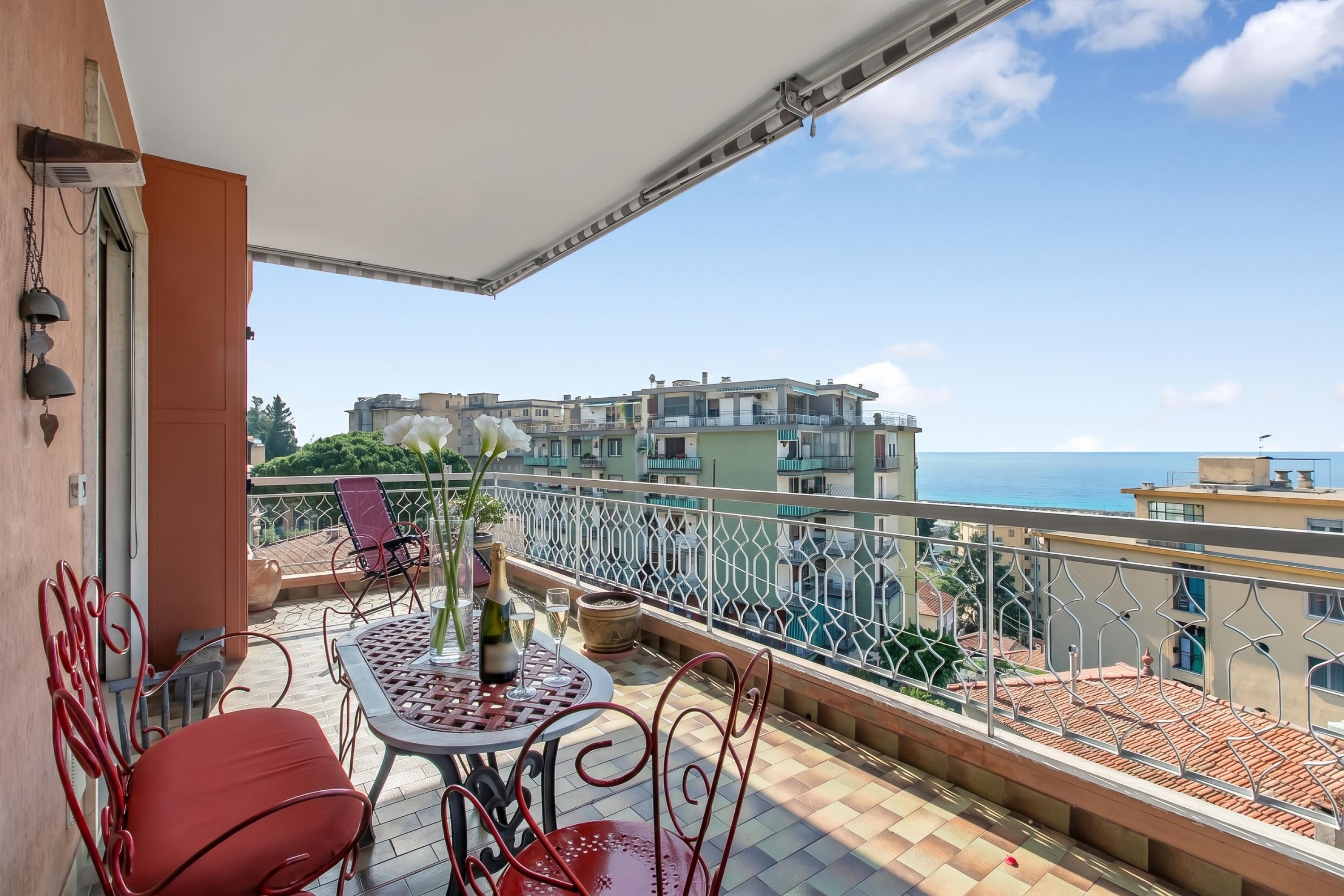 Un balcon avec une table, des chaises et une bouteille de champagne.