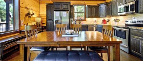Un interior de madera con una mesa de comedor, sillas, un banco, un refrigerador, un microondas y una estufa.