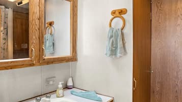 A bathroom with a wooden vanity, a mirror, a sink, and a towel rack.